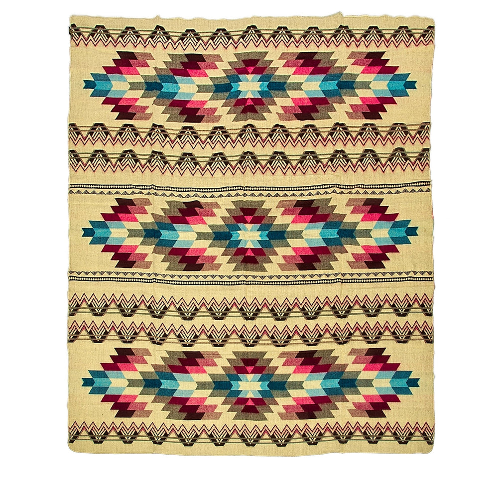 Ganze Ansicht der Alpaka-Wendedecke 'Antisana Lila' mit traditionellen Rauten- und Zickzack-Mustern auf hellem Hintergrund (Rückseite/helle Farbvariante).