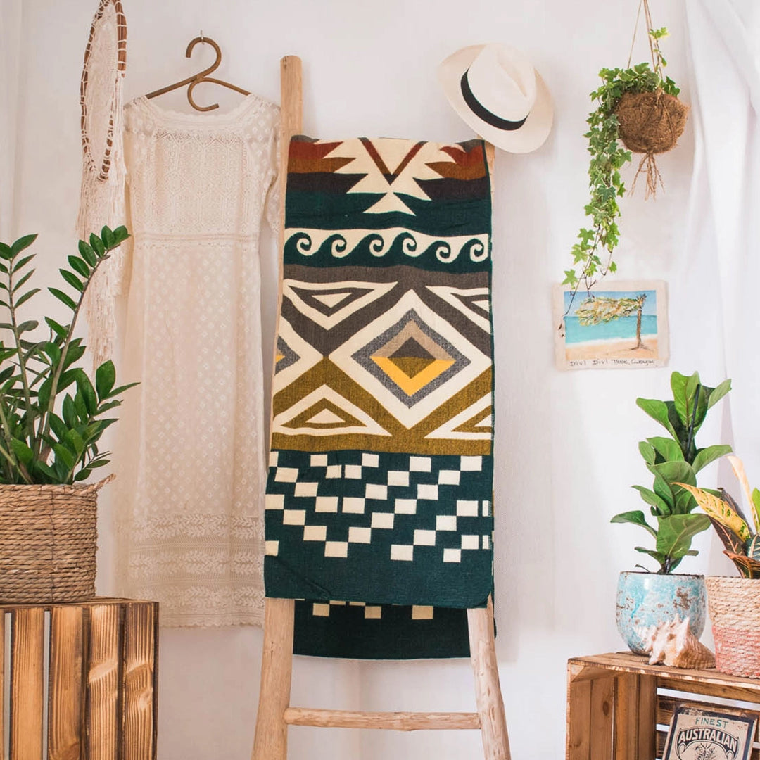 Alpaka-Decke 'Cayambe Grün' hängt auf einer Holzleiter als dekoratives Element in einem Boho-inspirierten Raum.