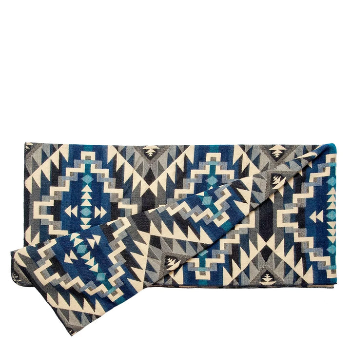 Zusammengefaltete Alpaka-Decke 'Chimborazo Black' mit geometrischem Design in verschiedenen Blau-, Grau- und Beigetönen.