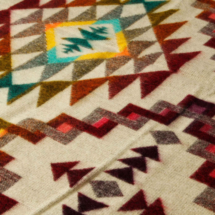 Nahaufnahme der beigen Seite der Alpaka-Decke 'Chimborazo Rosa', die feine Textur und detailreiche bunte Dreiecksmuster zeigt.