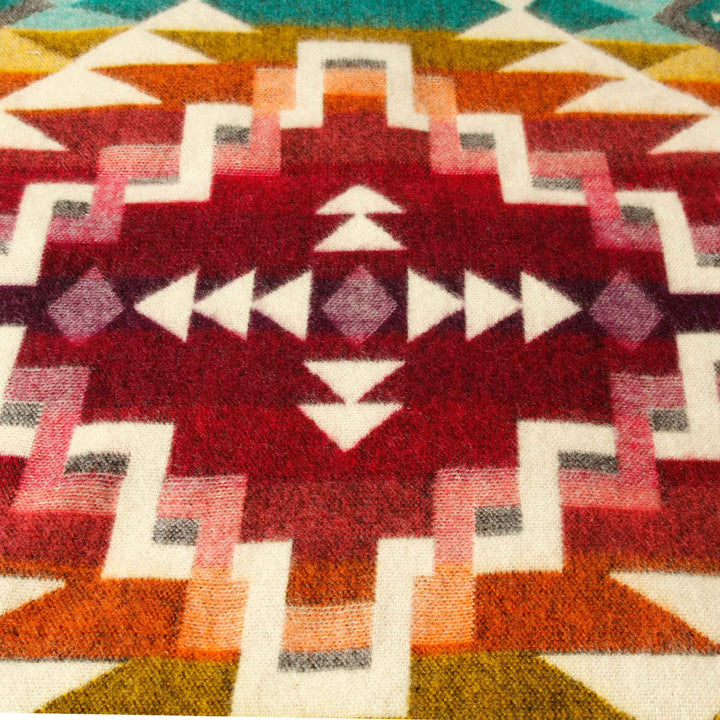 Detailaufnahme des zentralen, bordeauxroten Musters auf der dunklen Seite der Alpaka-Decke 'Chimborazo Rosa'.