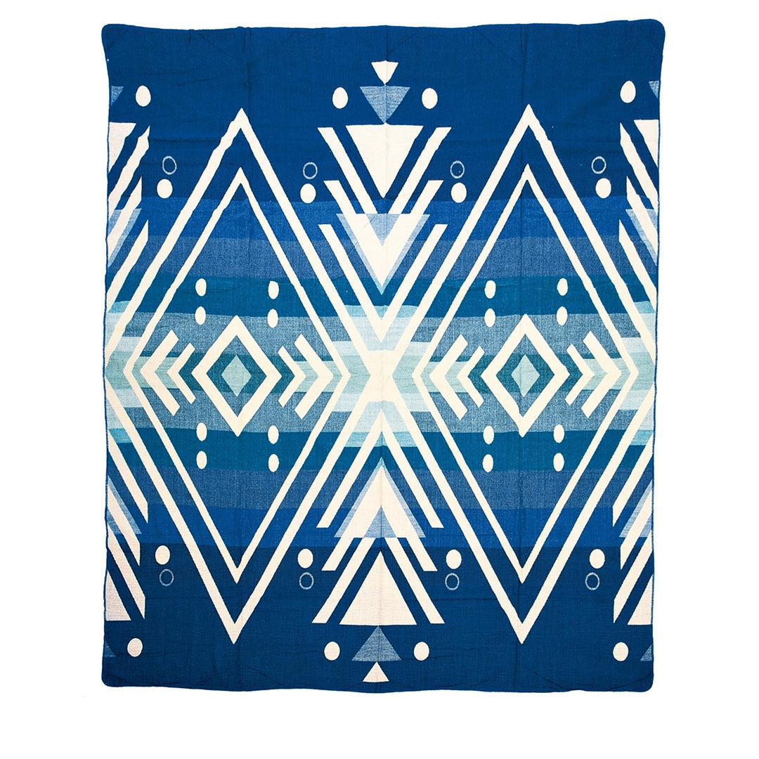 Ganze Ansicht der Alpaka-Wendedecke 'Imbabura Blau' mit großflächigem geometrischem Rautenmuster in Dunkelblau, Türkis und Beige.