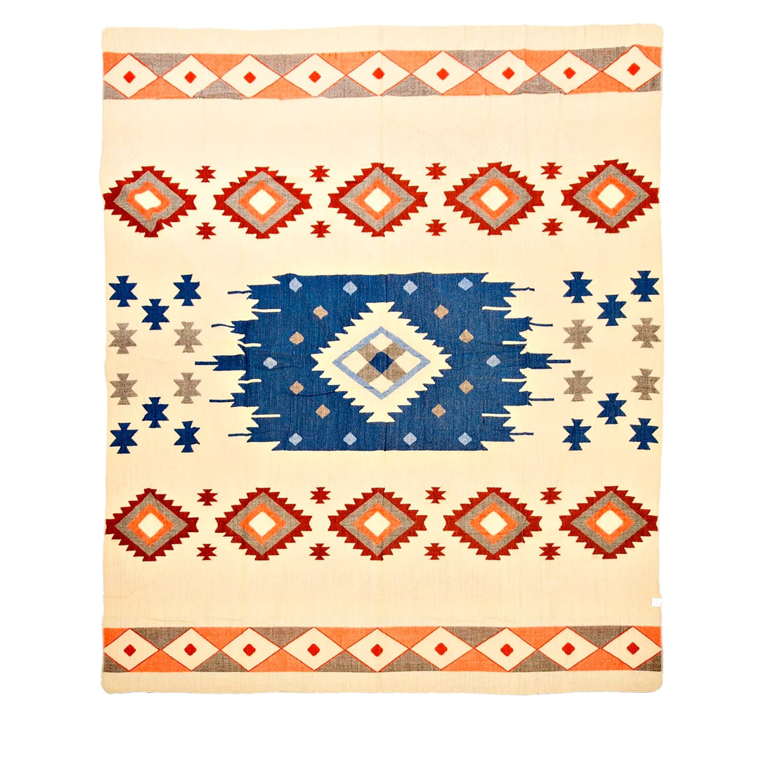 Alpaka-Decke mit einem beigen Hintergrund und einem zentralen blauen geometrischen Muster, umrahmt von Rauten-Bordüren in Rot, Orange und Grau
