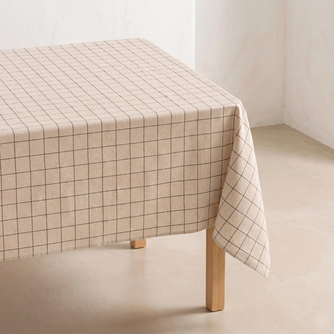 Beige Tischdecke mit feinem Karomuster auf hellem Holztisch in leerem Raum