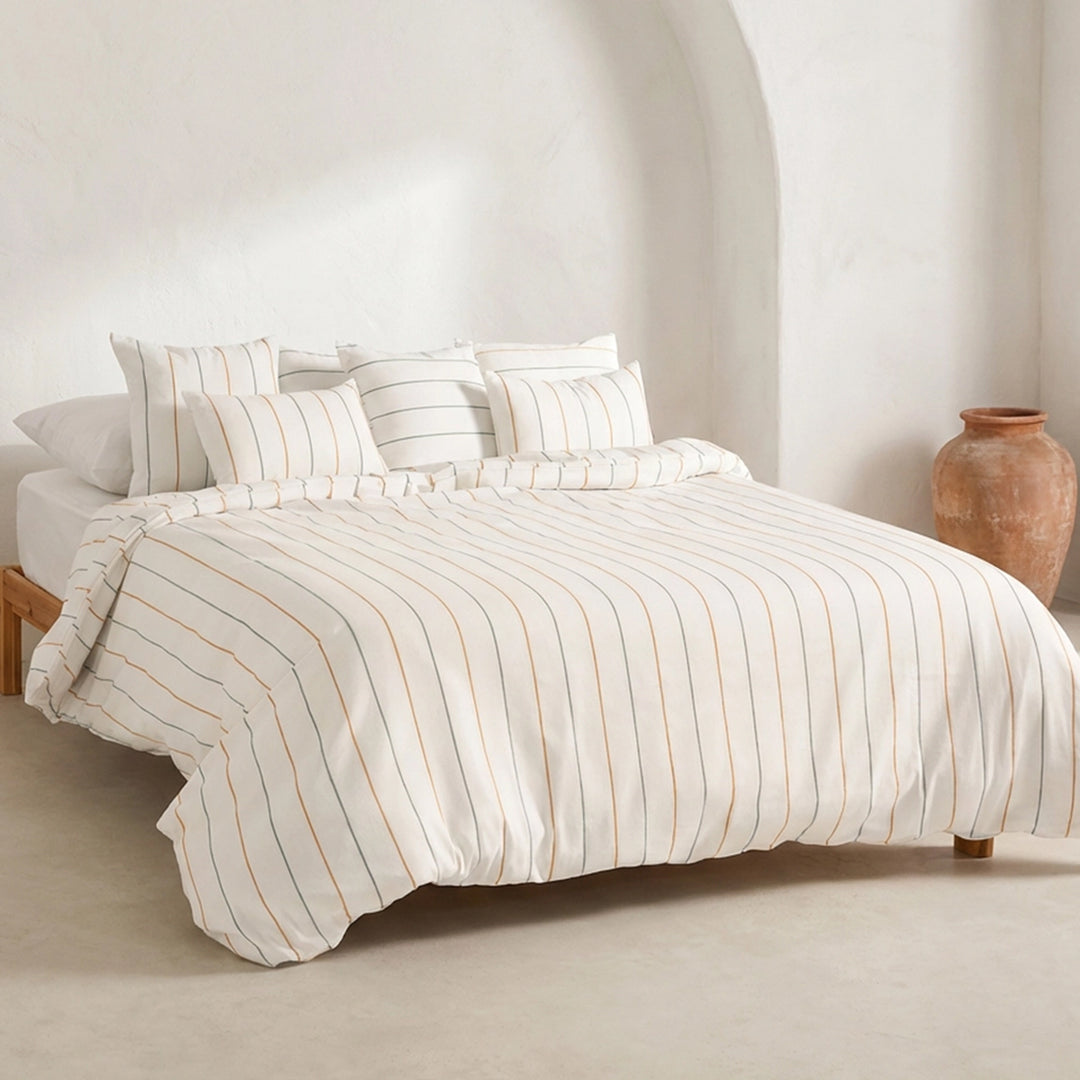 Weißer Bettbezug mit feinen Streifen und zwei passenden Kissen auf einem Bett
