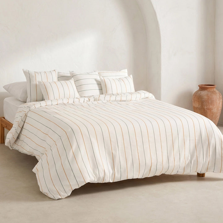 Weißer Bettbezug mit feinen Streifen und zwei passenden Kissen auf einem Bett