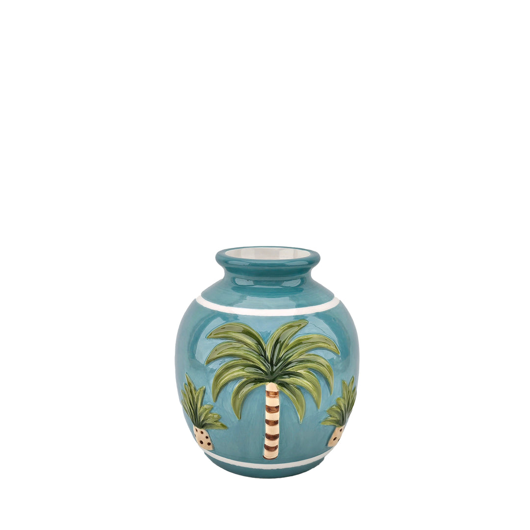 Runde blaue Vase mit Palmen, grünen Blättern und weißen Streifen vor weißem Hintergrund