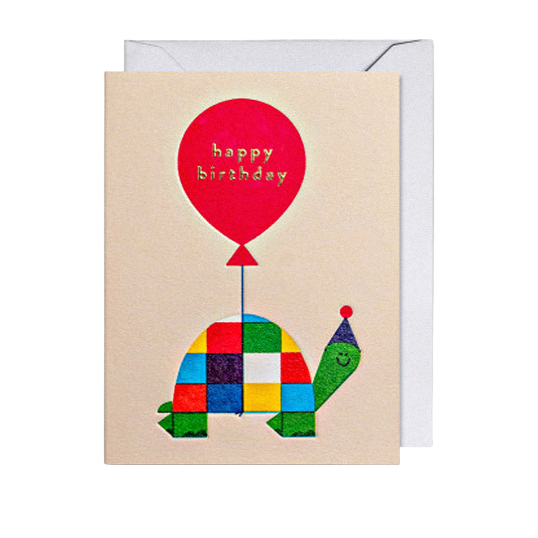 Geburtstagskarte mit fröhlicher Schildkröte in buntem Patchwork-Panzer, Partyhut und rotem „Happy Birthday“-Ballon.