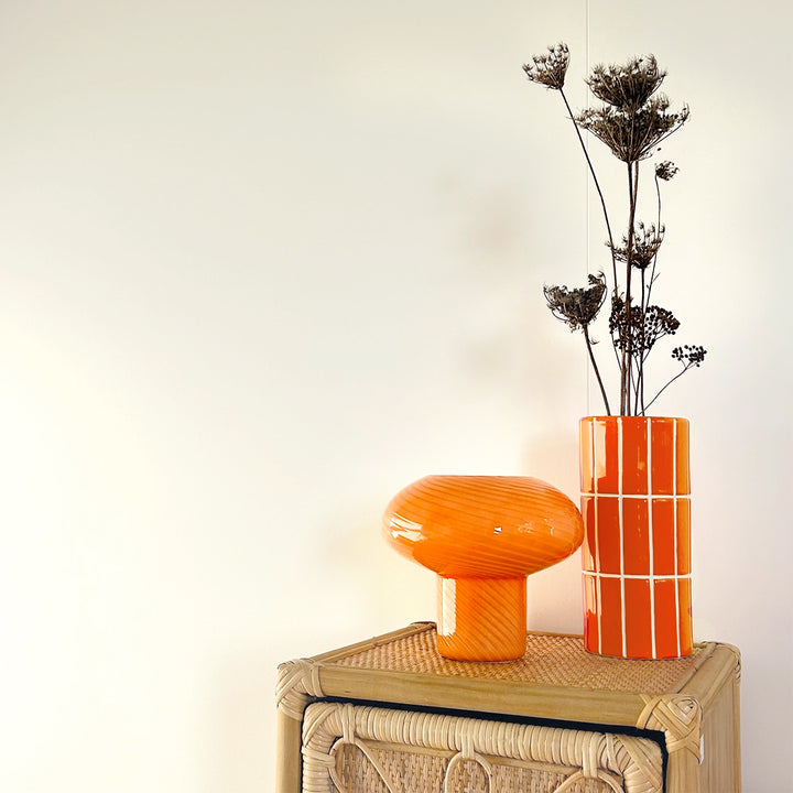Orangefarbene Vase mit weißem Linienraster