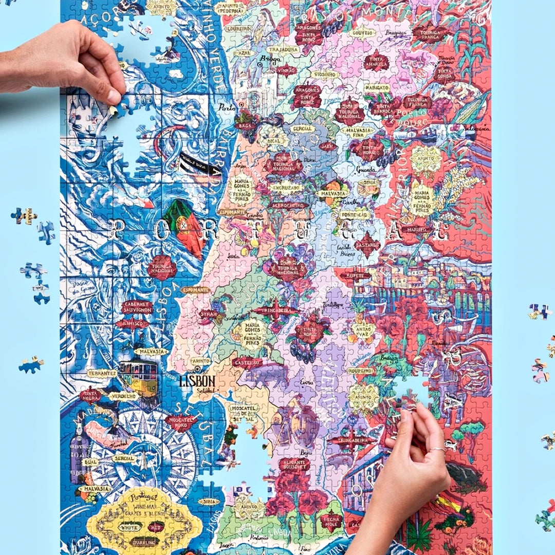 Arrangement aus der Puzzle-Box, dem unvollendeten Portugal-Puzzle und einem Begleitheft, das wichtige Rebsorten erklärt.