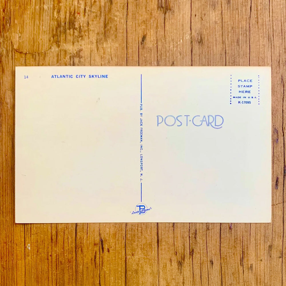 Rückseite von Vintage-Postkarte "Greetings from ATLANTIC CITY" mit einem breiten Blick auf die Küstenlinie, der Schriftzug zeigt Bilder von Menschenmengen und Attraktionen.