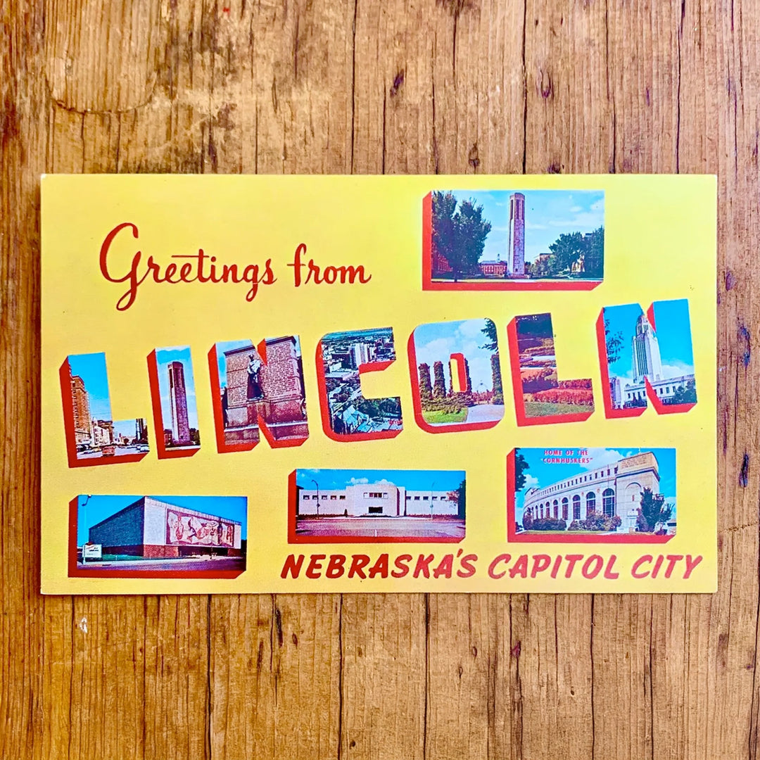 Vintage-Postkarte "Greetings from LINCOLN NEBRASKA'S CAPITOL CITY" auf gelbem Hintergrund. Die Buchstaben zeigen Bilder der Stadt, umrahmt von weiteren quadratischen Motiven.