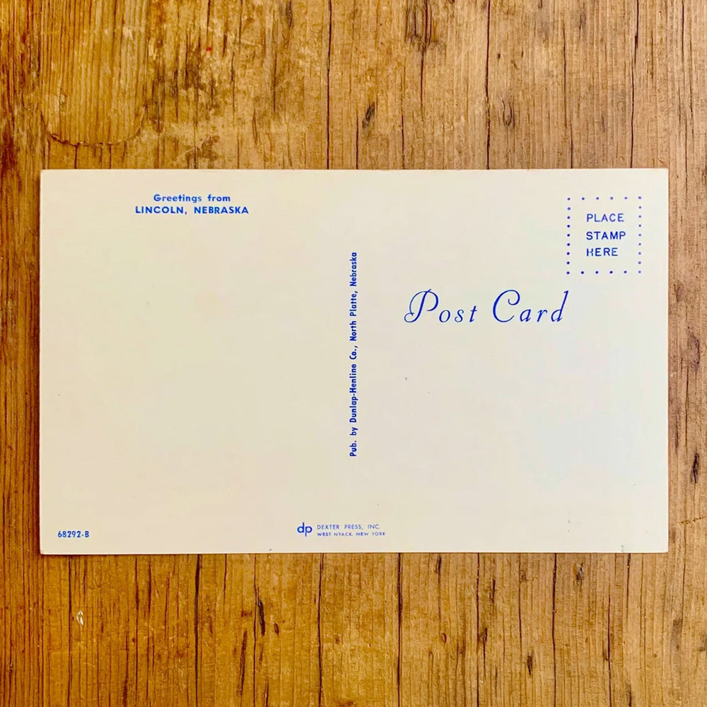 Rückseite von Vintage-Postkarte "Greetings from LINCOLN NEBRASKA'S CAPITOL CITY" auf gelbem Hintergrund. Die Buchstaben zeigen Bilder der Stadt, umrahmt von weiteren quadratischen Motiven.