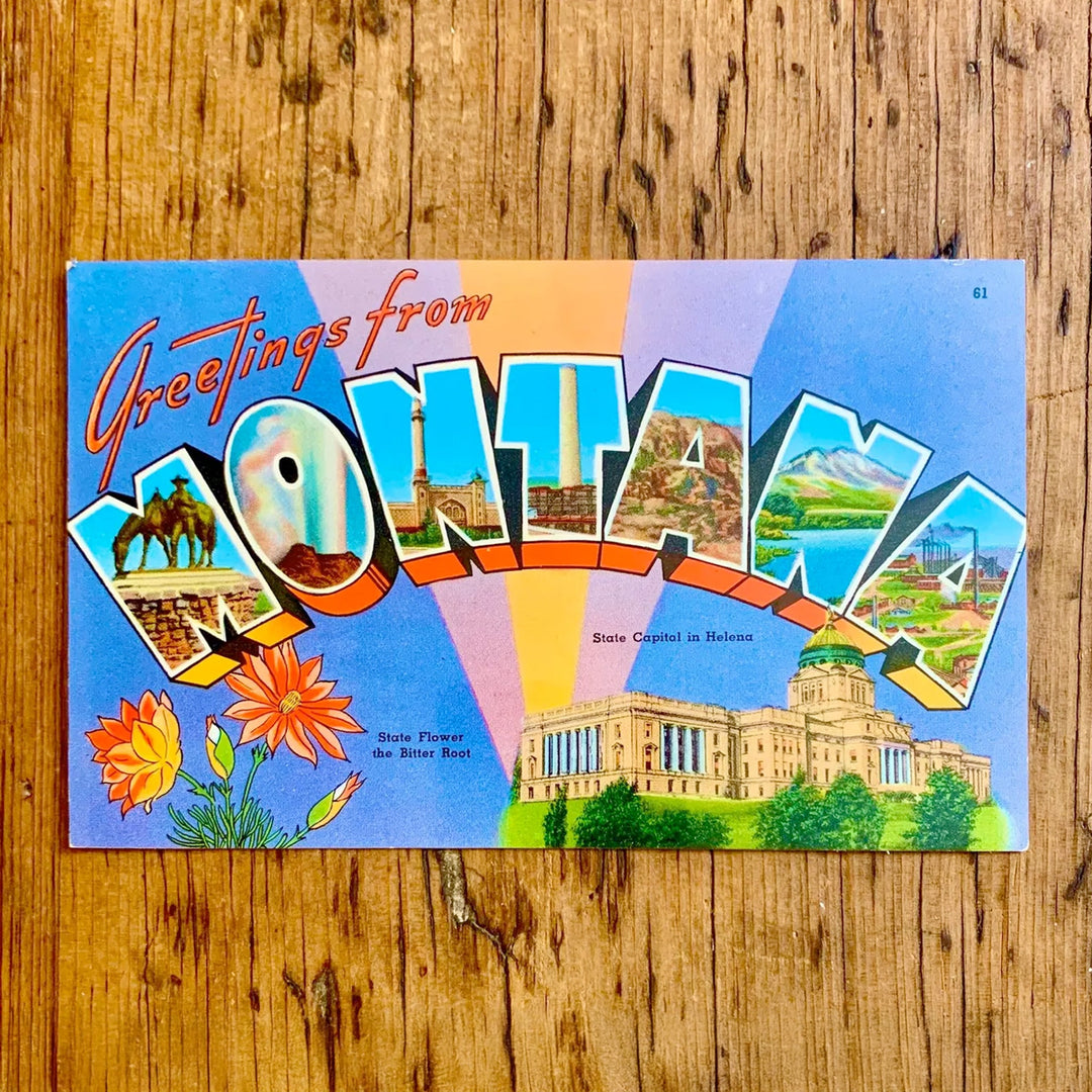 Vintage-Postkarte "Greetings from MONTANA" mit bunten Strahlen im Hintergrund. Die Buchstaben zeigen Landschafts- und Cowboy-Motive; im Vordergrund das State Capitol und die Staatsblume Bitter Root.